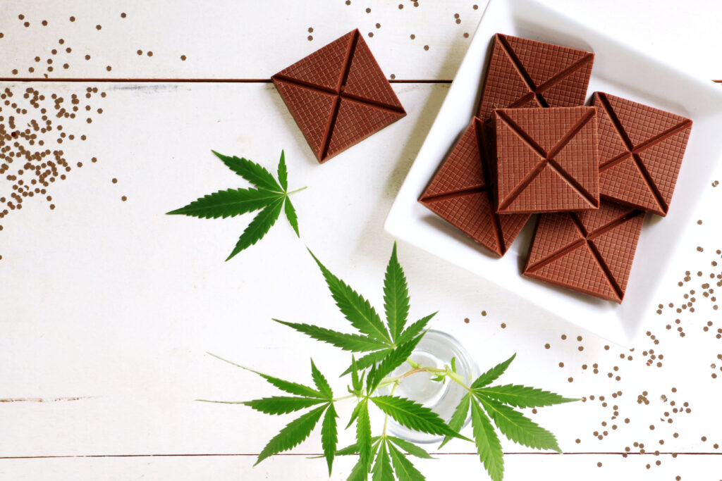 Cannabis leaves and chocolate bars laid out on a table.