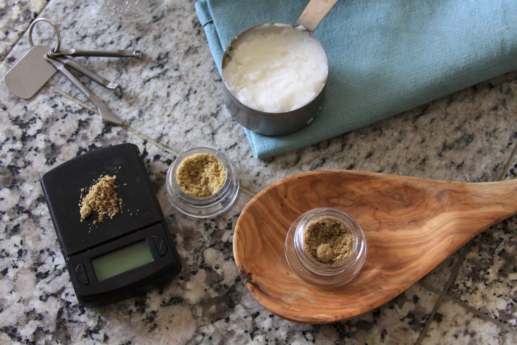 Cannabis kief on a digital scale with coconut oil on a marble countertop.